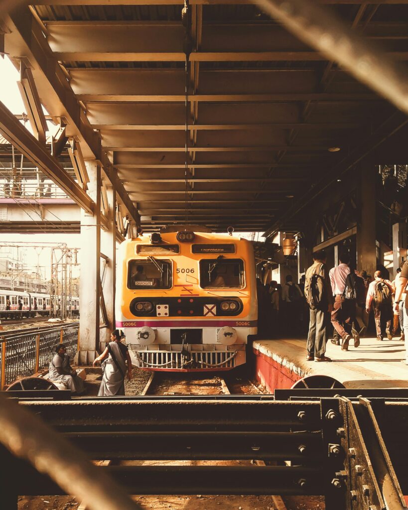 Passenger train at a bustling Mumbai railway platform during the day.